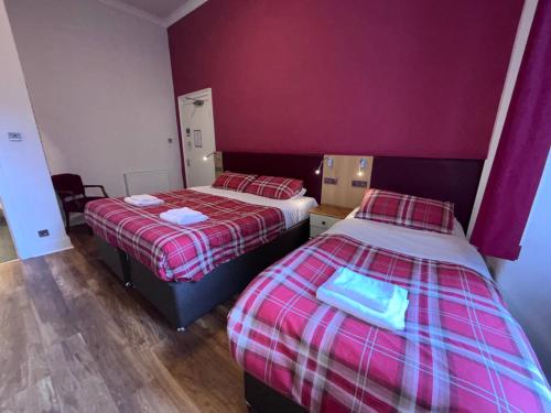 two beds in a room with purple walls at Regent House Hotel - City Centre Hotel in Edinburgh
