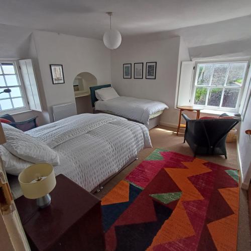 a bedroom with two beds and a colorful rug at The Old Post Office in Coverack