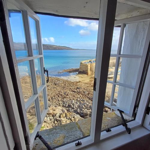 an open window with a view of the ocean at The Old Post Office in Coverack