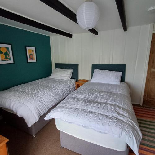 two beds in a bedroom with green and white walls at The Old Post Office in Coverack