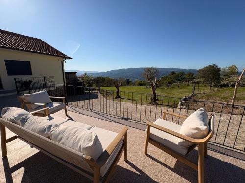 two beds and chairs on a patio with a fence at Quinta de Fonte Coberta in Ponte da Barca