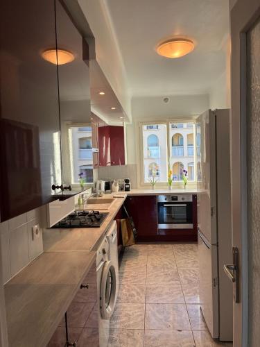 La cuisine est équipée de placards rouges et d'un four avec plaques de cuisson. dans l'établissement Sea View - Stylish Cannes Apt, à Cannes