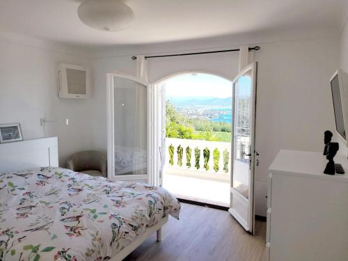 - une chambre avec un lit et une porte ouverte sur un balcon dans l'établissement Villa 140 m2 4 étoiles parking wifi - clim - piscine, à Roquebrune-sur Argens