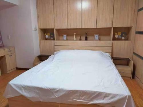 a bedroom with a large white bed with wooden cabinets at R&R Entire Rental Unit in Manila