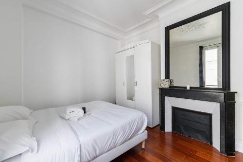 - une chambre avec un lit blanc et une cheminée dans l'établissement Appartement coeur paris 16 victor hugo - 4P, à Paris