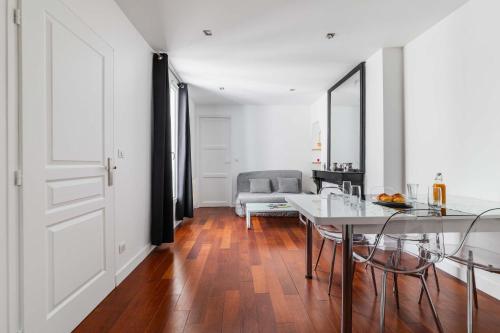 un salon blanc avec une table et des chaises dans l'établissement Appartement coeur paris 16 victor hugo - 4P, à Paris