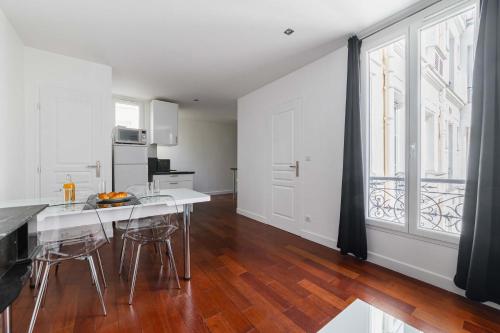 une cuisine avec une table et des chaises ainsi qu'une grande fenêtre dans l'établissement Appartement coeur paris 16 victor hugo - 4P, à Paris