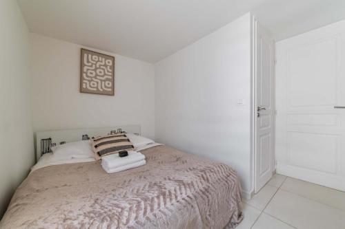 une chambre blanche avec un lit avec deux serviettes dessus dans l'établissement Appartement Cosy metro saint paul - 4P - Paris 4, à Paris