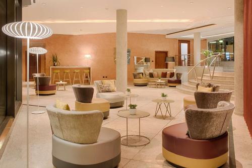 a lobby with chairs and tables in a building at NH Lecco Pontevecchio in Lecco