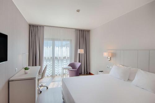 a hotel room with a bed and a desk and a window at NH Lecco Pontevecchio in Lecco