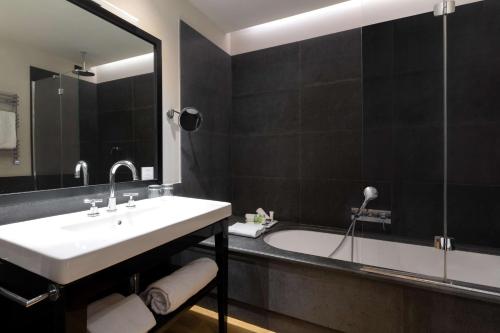 a bathroom with a sink and a bath tub at NH Collection Torino Piazza Carlina in Turin