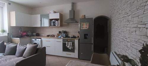 une cuisine et un salon avec un canapé et un mur de briques dans l'établissement Pivoinie, à Fleury-les-Aubrais