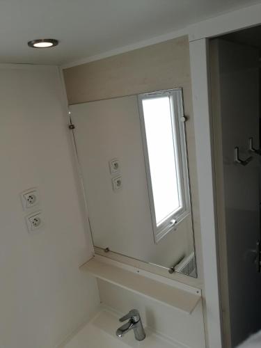 une salle de bain avec un miroir et un lavabo dans l'établissement bungalow au soleil camping les dunes, à Torreilles