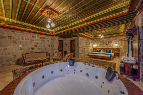 a large bath tub in a room with a bedroom at Latona Stone Palace in Nevsehir