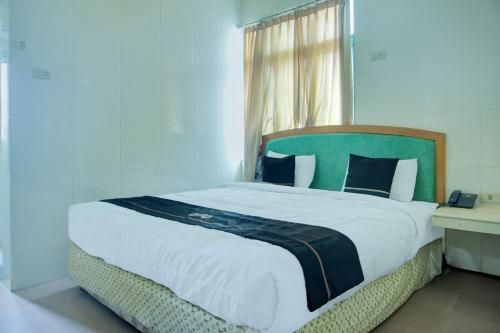 a bedroom with a large bed with a green headboard at Dancenterak Palembang Near Jembatan Ampera Formerly Azzura Hotel in Palembang