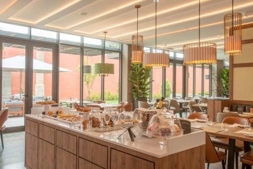 Un restaurante con mesas, sillas y ventanas. en NH Porto Jardim, en Oporto