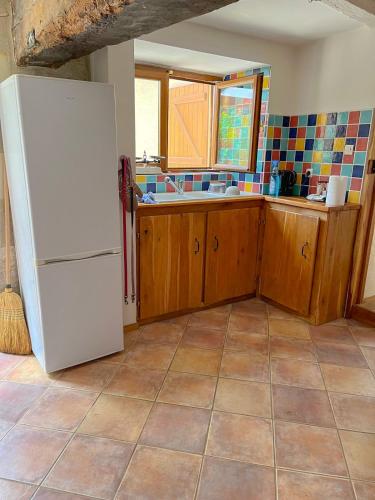 La cuisine est équipée d'un réfrigérateur blanc et de placards en bois. dans l'établissement Le Petit Nid, à Romagne