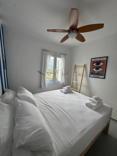 a bedroom with a white bed with a ceiling fan at Casa Azul in Kokkari