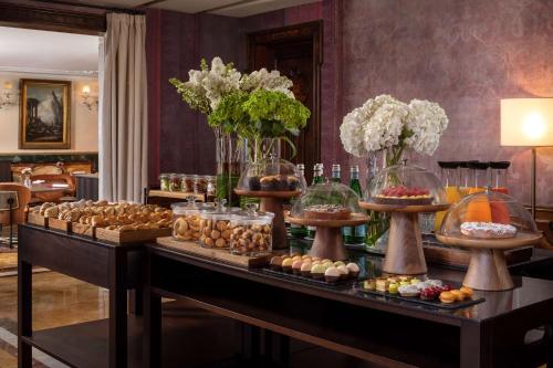 ヴェネツィアにあるNH Collection Grand Hotel Palazzo Dei Dogiの花瓶に花が飾られたテーブルの上にビュッフェ形式の料理が並んでいる