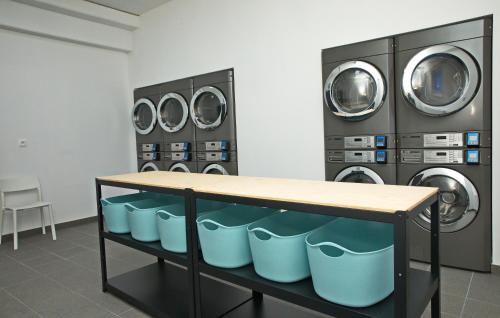 a laundry room with three washing machines and a table at Hostel Optimum Devínska in Devin