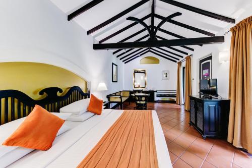 a bedroom with a large bed with orange pillows at Cinnamon Lodge Habarana in Sigiriya