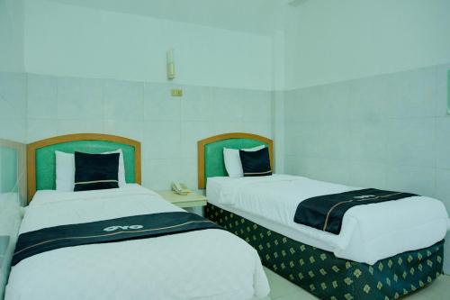 two beds sitting next to each other in a room at Dancenterak Palembang Near Jembatan Ampera Formerly Azzura Hotel in Palembang