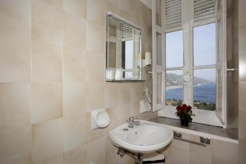 Un baño con lavabo y ventana. en Villa Astoria, en Taormina