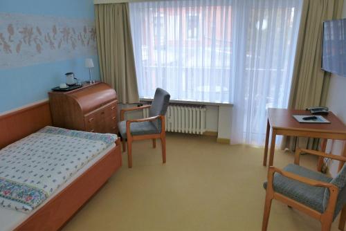 a bedroom with a bed and a desk and a table at Hotel Am Kurpark in Malente