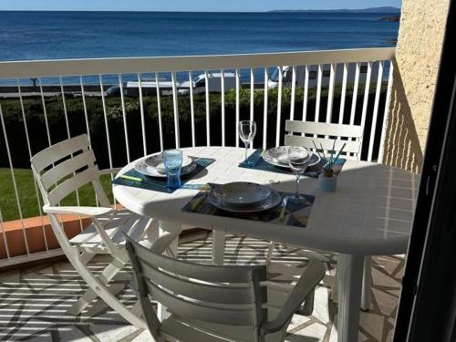 une table blanche et des chaises sur un balcon avec l'océan dans l'établissement Vue mer 180 degrés - Wifi - Parking, à Saint-Raphaël