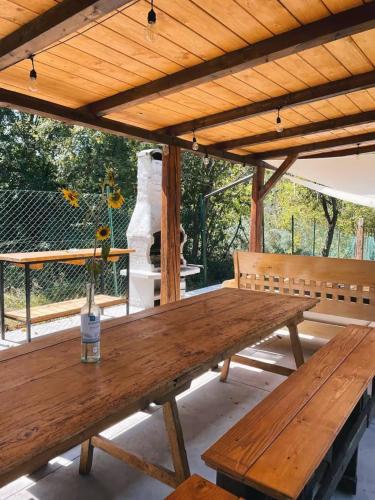 a wooden picnic table on a patio with benches at Casale Viozzi - Casa Vacanze con piscina nelle Marche in Montefalcone Appennino
