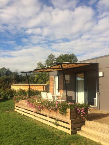 a small house with a deck with flowers at Camping Du Paquier Fané in Chagny