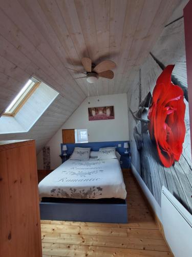 une chambre avec un lit avec une fleur rouge sur le mur dans l'établissement Les Roses Des Bois, à Murat-le-Quaire