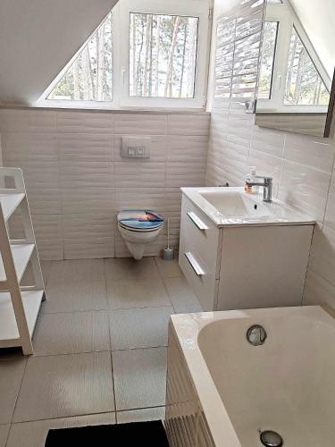 a white bathroom with a toilet and a sink at Villa Alex in Siófok