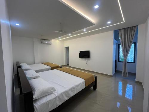 ein Schlafzimmer mit zwei Betten und einem Fernseher an der Wand in der Unterkunft Sakthi Guest House in Tiruvannāmalai