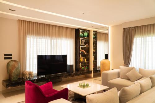 a living room with a couch and chairs and a television at La Villa in Mangalore