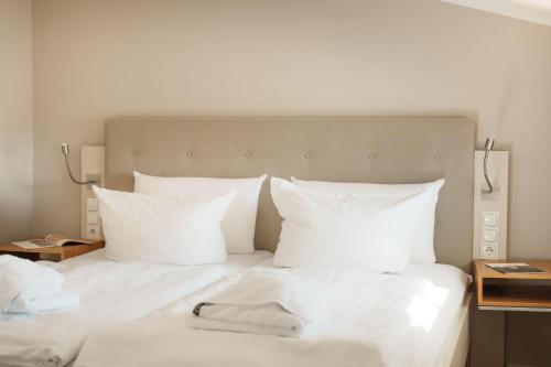 a white bed with white sheets and pillows at Hotel Meersinn - Binz in Binz