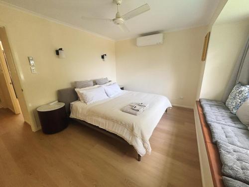 a small bedroom with a bed and a couch at Spacious home in Shailer Park in Tanah Merah
