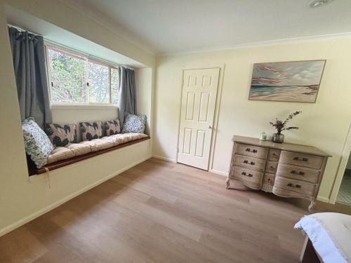 a bedroom with a couch and a window and a dresser at Spacious home in Shailer Park in Tanah Merah