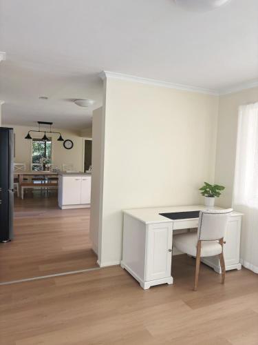 a living room with a white desk and a kitchen at Spacious home in Shailer Park in Tanah Merah