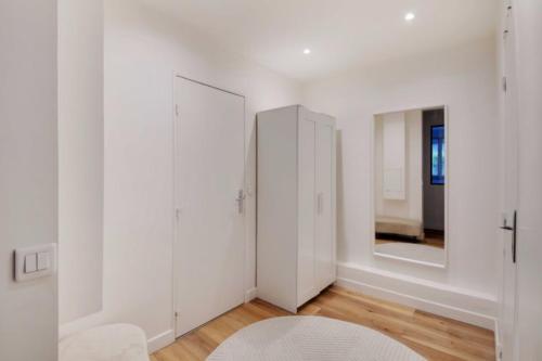 Cette chambre blanche est dotée de murs blancs et d'un miroir. dans l'établissement Beautiful 3BR 8P Nation Apartment, à Paris