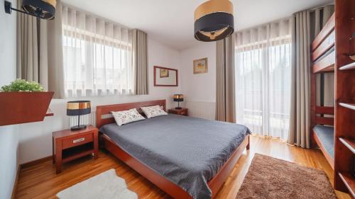 a bedroom with a bed and two windows at Sywarne, Sun & Snow in Kościelisko