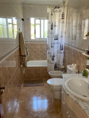 a bathroom with a toilet and a tub and a sink at Charming duplex with pool in Torrevieja