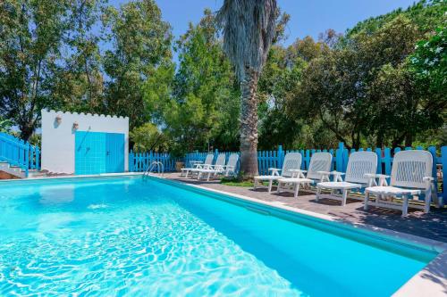 a swimming pool with chairs and a tree at Agriturismo Costa del Sud in Teulada