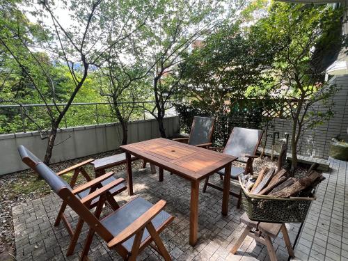 a wooden table and chairs on a patio at ゲストハウス熱海西山ガーデン in Atami