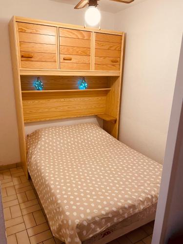 Ce petit lit se trouve dans un dortoir doté d'une armoire en bois. dans l'établissement Le Palm Beach vue mer le Barcares, au Barcarès