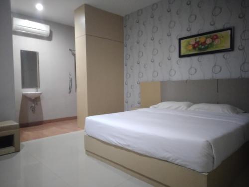 a bedroom with a white bed and a painting on the wall at Tembok Batu Residence in Jetis