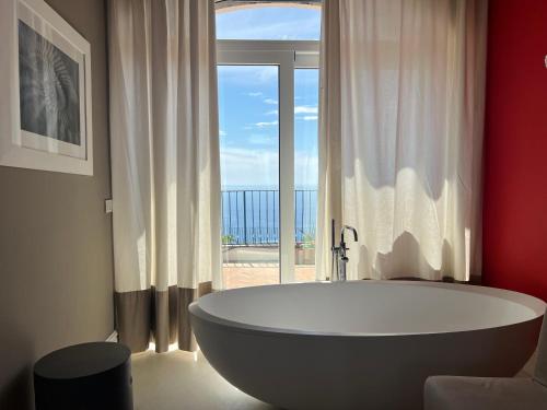 a bath tub in a bathroom with a large window at Hotel Della Piccola Marina in Capri