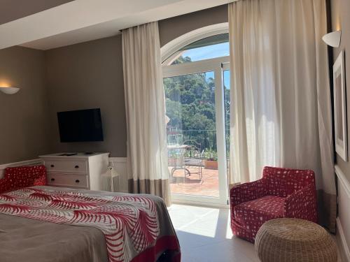 a bedroom with a bed and a chair and a window at Hotel Della Piccola Marina in Capri