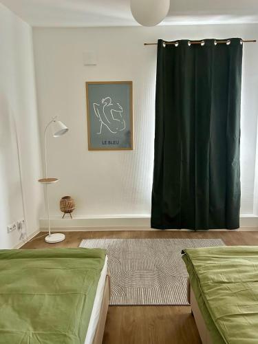 a bedroom with two beds and a green curtain at Apartment über 3-Etagen genau im Zentrum! in Neumünster