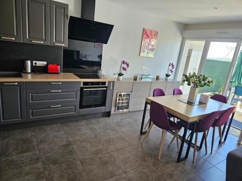 - une cuisine avec une table et des chaises violettes dans la chambre dans l'établissement L'Escapade Enchantée, à Leyment